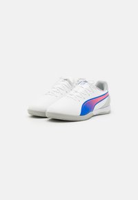 Zapatillas deportivas blancas con una superficie lisa, con un diseño de rayas azul y rosa, suela gris texturizada y un sistema de cordones tradicional.