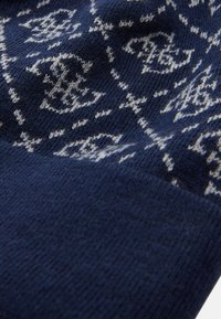 Tejido de punto azul marino con patrones geométricos blancos. Textura suave, con una transición suave de áreas con patrón a áreas sólidas.