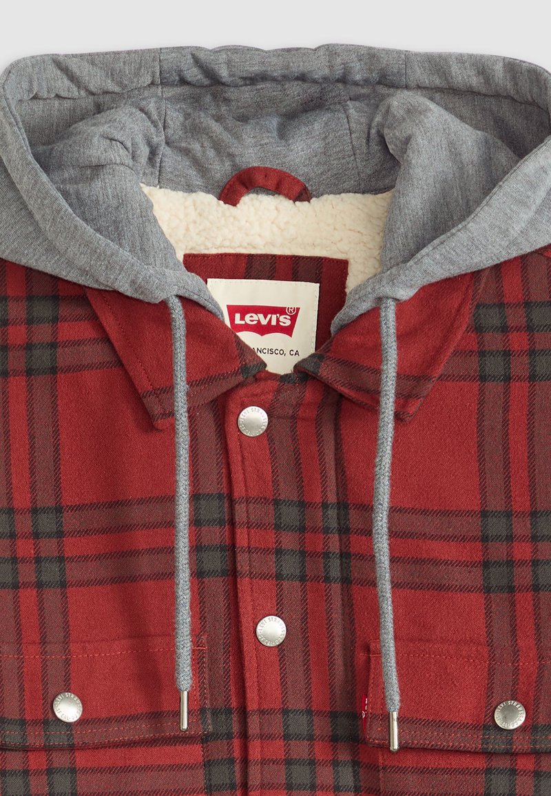 Czerwona i czarna koszula flanelowa w kratę z szarym kapturem, z miękką podszewką, srebrnymi zatrzaskami i podwójnymi kieszeniami na piersi.