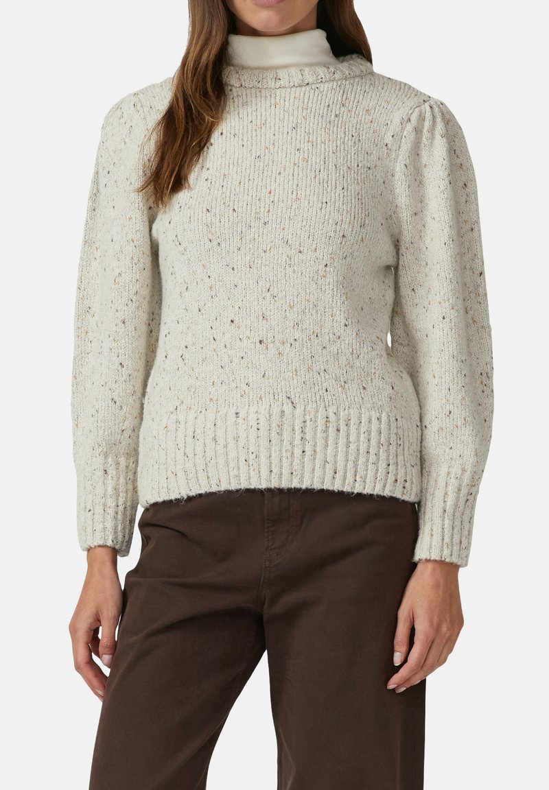 Lichtbeige gebreide trui met een hoge hals, geribbelde manchetten en zoom, met kleurvlekken door de stof voor extra textuur.