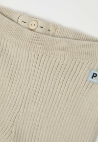 Beige neulepaita, jossa on ribbikuviointi, pyöreä pääntie ja nappisulku. Mukana on etiketti, jossa on sininen kirjain "P".