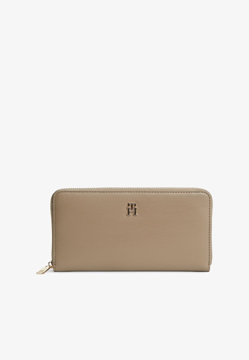 Portefeuille rectangulaire en cuir beige avec fermeture éclair sur tout le pourtour et initiales en métal doré "TH" centrées sur le devant.