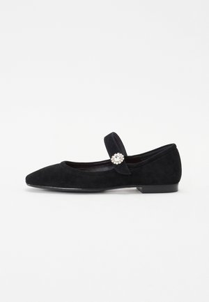 Ballet flats em camurça preta com bico apontado, tira atravessando o pé e um grande detalhe decorativo em forma de gema na tira. Salto baixo e plano.