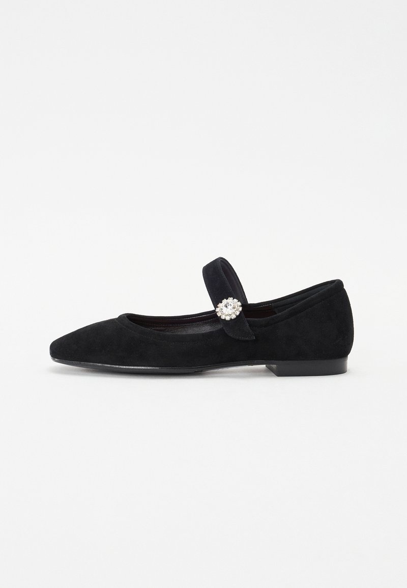 Ballet flats em camurça preta com bico apontado, tira atravessando o pé e um grande detalhe decorativo em forma de gema na tira. Salto baixo e plano.