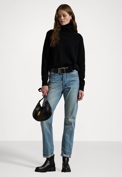 Pulover negru cu guler înalt, blugi de denim ușor albaștri, bocanci din piele negri și o geantă neagră cu un accent auriu; siluetă casual, ajustată.