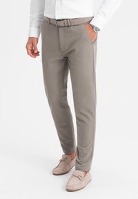 Pantalons en coton gris au design ajusté, avec des poches latérales et une ceinture assortie. Associés à des chaussures en cuir gris clair.