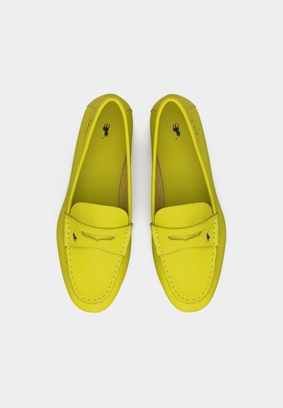 Ζευγάρι λαμπερών κίτρινων δερμάτινων μοκασίνων με ραμμένες λεπτομέρειες και μικρά κεντημένα λογότυπα με άλογο, εμφανιζόμενα από πάνω σε λευκό φόντο.