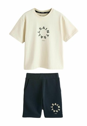Cremeweißes Baumwoll-T-Shirt mit rundem schwarzem Logoaufdruck, kombiniert mit marineblauen Shorts mit einem ähnlichen Logo in Beige. Weiches, lässiges Design.