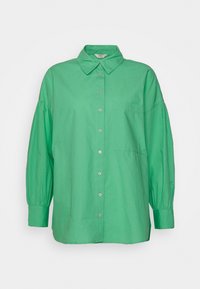 Green oversized button-up shirt made of cotton, featuring a collar, long puff sleeves, and a single chest pocket. Smooth texture.