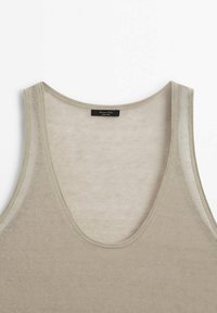 Débardeur en maille beige sans manches avec encolure dégagée, montrant le haut du devant et les bords cousus sur fond blanc.