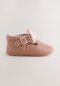 Chaussure de bébé en cuir rose clair avec un bout arrondi, des découpes festonnées et une bride latérale avec une boucle en métal doré et un accent nœud.