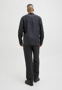 Camisa de lino gris oscuro y pantalones a juego, de corte relajado con puños abotonados, textura suave y perneras rectas, combinados con zapatos negros.