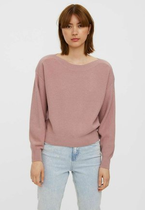 Lyserød strikket sweater med en afslappet pasform, rund hals og ribbet kant. Båret over lyseblå denimjeans med struktureret stof.