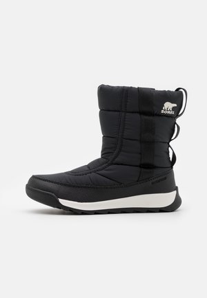 Botte d'hiver noire isolée mi-mollet avec semelle blanche, matériau imperméable et logo Sorel sur le dessus.