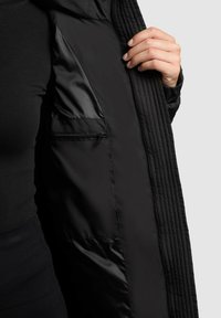 Fekete párnázott dzseki steppelt mintával és selymes béléssel. Belső zsebe cipzárral záródik, és sima tapintású.