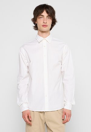 Witte lange mouwen blouse met een standaardkraag, een gladde textuur en een subtiele logo op de borst, gecombineerd met lichtbeige broek.