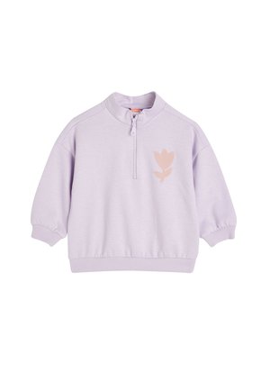 Sudadera lila con cuello de media cremallera, corte holgado y puños acanalados. Presenta un diseño floral en rosa en la parte frontal. Tela suave y lisa.