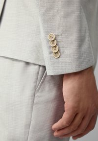 Hellgraue, strukturierte Sakkoärmel mit vier sandfarbenen Knöpfen und einem dezenten blauen Karomuster. Tailored Fit mit modernem Design.