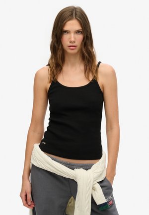 Sort ribbet tanktop med tynde stropper, med en rund halsudskæring og et lille broderet logo i kanten, båret med grå sweatpants.