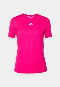 Světlé růžové sportovní tričko s krátkým rukávem a kulatým výstřihem, se středově umístěným bílým logem Adidas na hrudi.