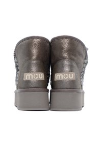 Un paio di stivaletti metallici grigi alla caviglia con suole spesse e etichetta del marchio "mou" sul retro, mostrati da dietro su sfondo bianco.