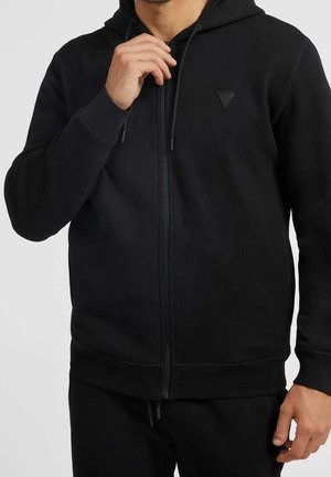 Schwarze Zip-Hoodie aus weichem Stoff, mit Kapuze, Fronttaschen und kleinem Logo auf der Brust. Strukturiert Oberfläche, verstellbare Kordeln.