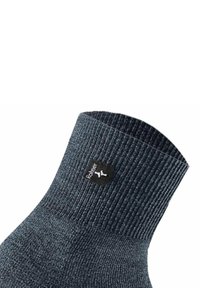 Calzino grigio scuro con texture a coste, dotato di un'etichetta nera con marchio vicino alla parte superiore. Il materiale sembra morbido ed elastico.