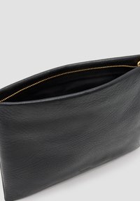Zwarte leren clutch tas met een textuurafwerking, voorzien van een gouden ritsluiting aan de bovenkant en een gladde, minimalistische binnenkant.