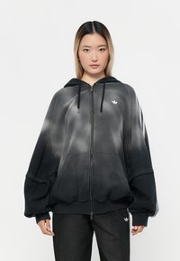 Black and gray gradient zip-up hoodie with a drawstring hood, oversized design, and a small white logo on the chest. Ribbed cuffs and hem.