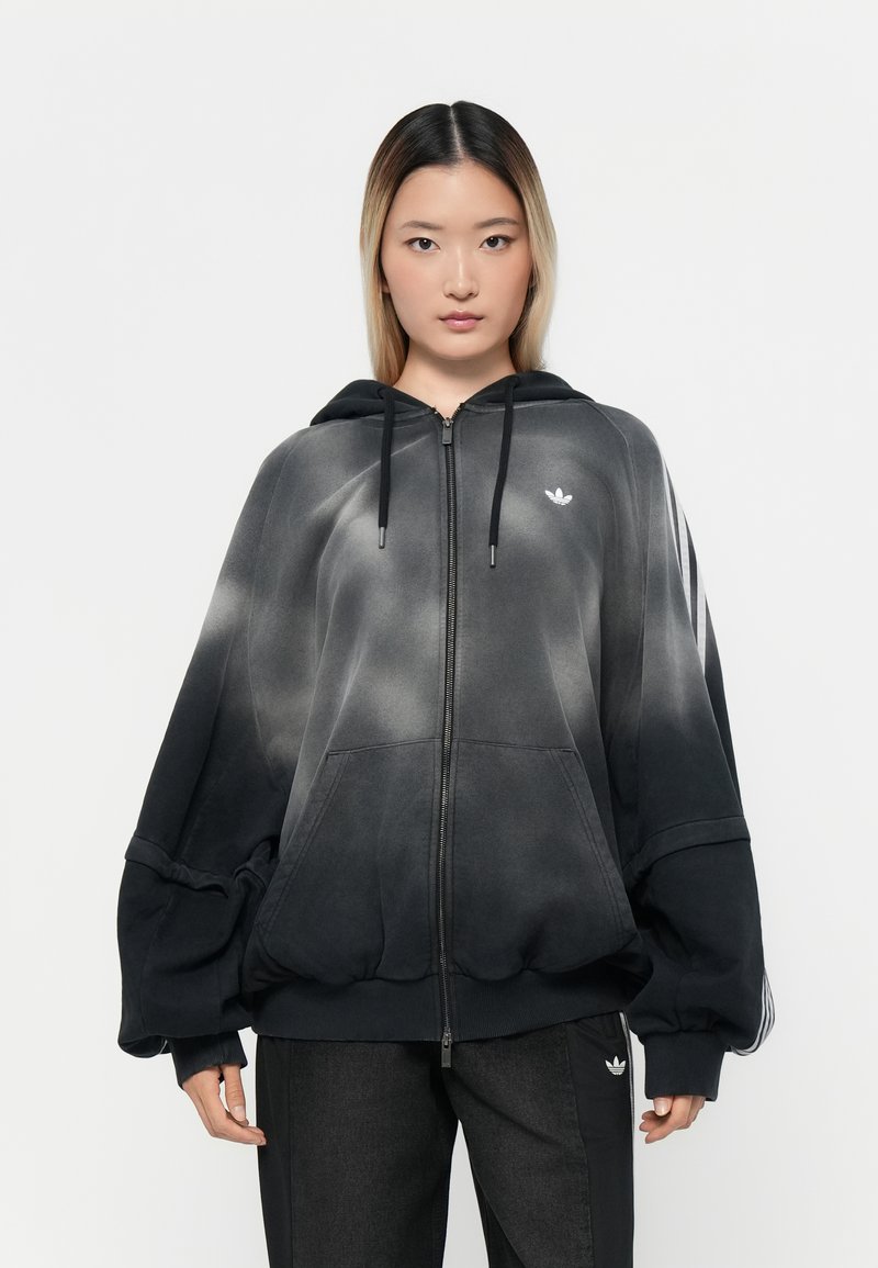 Zwart en grijs gradient rits hoodie met een trekkoordkap, oversized ontwerp en een klein wit logo op de borst. Geribbelde manchetten en zoom.