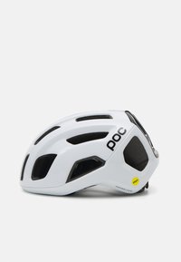 Casco de ciclismo blanco con múltiples puertos de ventilación, diseño aerodinámico elegante, relleno interior negro y una etiqueta de seguridad MIPS amarilla.