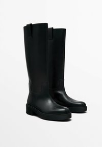 Black knee-high boots made of smooth leather, featuring a rounded toe, block heel, and back pull tab for easy wear.
