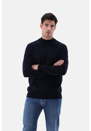 Marineblauer Rundhals-Pullover aus weichem Strickmaterial mit langen Ärmeln, gerippten Bündchen und Saum, kombiniert mit hellblauen Jeans.