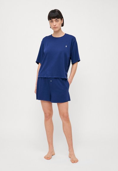 Mörkblå kortärmad T-shirt med lös passform, i kombination med matchande shorts som har knapprad. Mjuk tyg med en minimal logotyp.