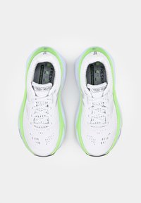 White running shoes with green accents, breathable mesh upper, cushioned soles, and perforated detailing for ventilation. Features visible branding.