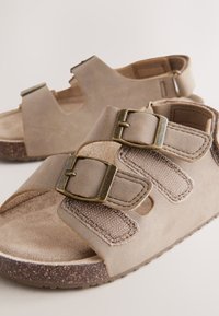 Sandali beige con doppi cinturini con fibbia, materiale scamosciato e sottopiede testurizzato. Caratteristiche: punta rotonda e suola in gomma marrone con motivo.