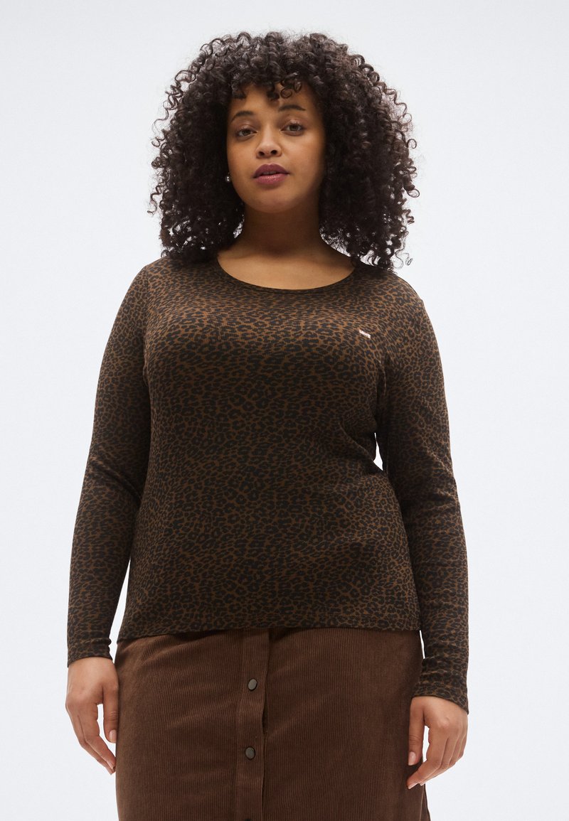 Ruda ilgomis rankovėmis palaidinė su juodu leopardų raštu. Audinys atrodo minkštas; apvalus kaklo iškirpimas. Dėvima su ruda korduro linijine sijonu.