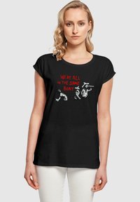 Black short-sleeve t-shirt featuring white and red graphic text: "WE'RE ALL IN THE SAME BOAT," with illustrated figures in action.