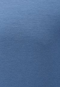 Κοντινό πλάνο μπλε πλεκτού υφάσματος που δείχνει λεπτή, ομοιόμορφη υφή και διακριτικά οριζόντια και κάθετα ραφικά μοτίβα.