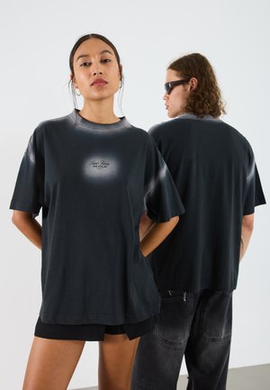 Übergröße schwarzes T-Shirt aus Baumwolle mit einem verlaufenden Lichteffekt und Logo auf der Vorderseite. Lockerer Schnitt mit kurzen Ärmeln und rundem Halsausschnitt.