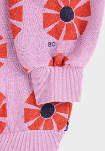 Ružová mikina s odvážnymi červenými a tmavomodrými kvetinovými vzormi, s rebrovanými manžetami a mäkkou textúrou. Malé logo "BC" blízko manžety.