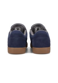 Navy blue suede sneakers with grey textile lining, brown rubber soles, minimalistic design, and reinforced stitching details at the heel.