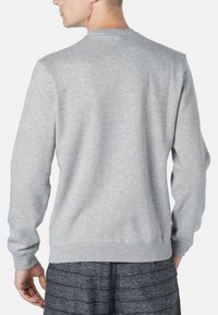 Sudadera gris con mangas largas y cuello redondo. Tejido suave y texturizado con un corte relajado. Sin gráficos ni acentos visibles.
