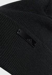 Berretto lavorato a maglia nero realizzato in tessuto morbido e testurizzato; presenta un'etichetta metallica nera con un logo posizionata di lato.