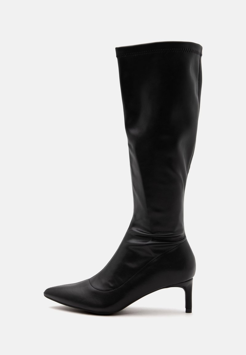 Botte en cuir noire montante au genou avec un bout pointu et un talon moyen fin sur un fond clair uni.