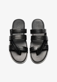Chanclas de slide negras hechas de cuero sintético, que presentan tres tiras texturizadas con un patrón de cocodrilo. Suela suave con marca elevada.