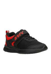 Scarpa da ginnastica nera con accenti rossi, materiale in rete, punta rotonda, cinturino in Velcro e suola in gomma testurizzata. Design leggero per l'abbigliamento attivo.
