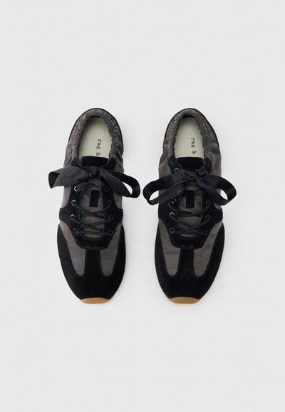 Zapatillas deportivas en negro y gris, con una combinación de ante y tela en la parte superior, cierre de cordones y cintas planas negras. Cuello ligeramente acolchado.