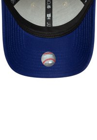 Casquette de baseball bleue avec un visière noire, arborant un autocollant rond affichant un design de baseball sur le devant. Texture de tissu doux, forme structurée.