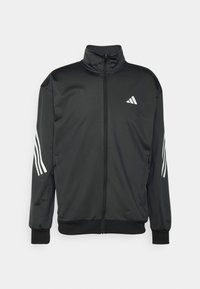 Giacca sportiva nera con colletto alto, zip completa, tasche con zip e dettagli bianchi a tre strisce sulle maniche. Tessuto liscio e leggero.